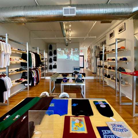 Apparel, hats, and accessories laid out on tables inside a Blacklist shop