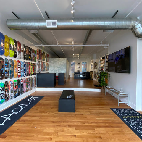 Wall of skateboard decks and the Blacklist logo painted on the floor mats inside the Lawrenceburg shop