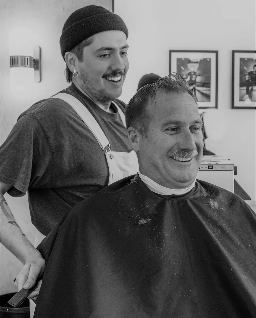 A barber and client sharing a laugh mid-haircut