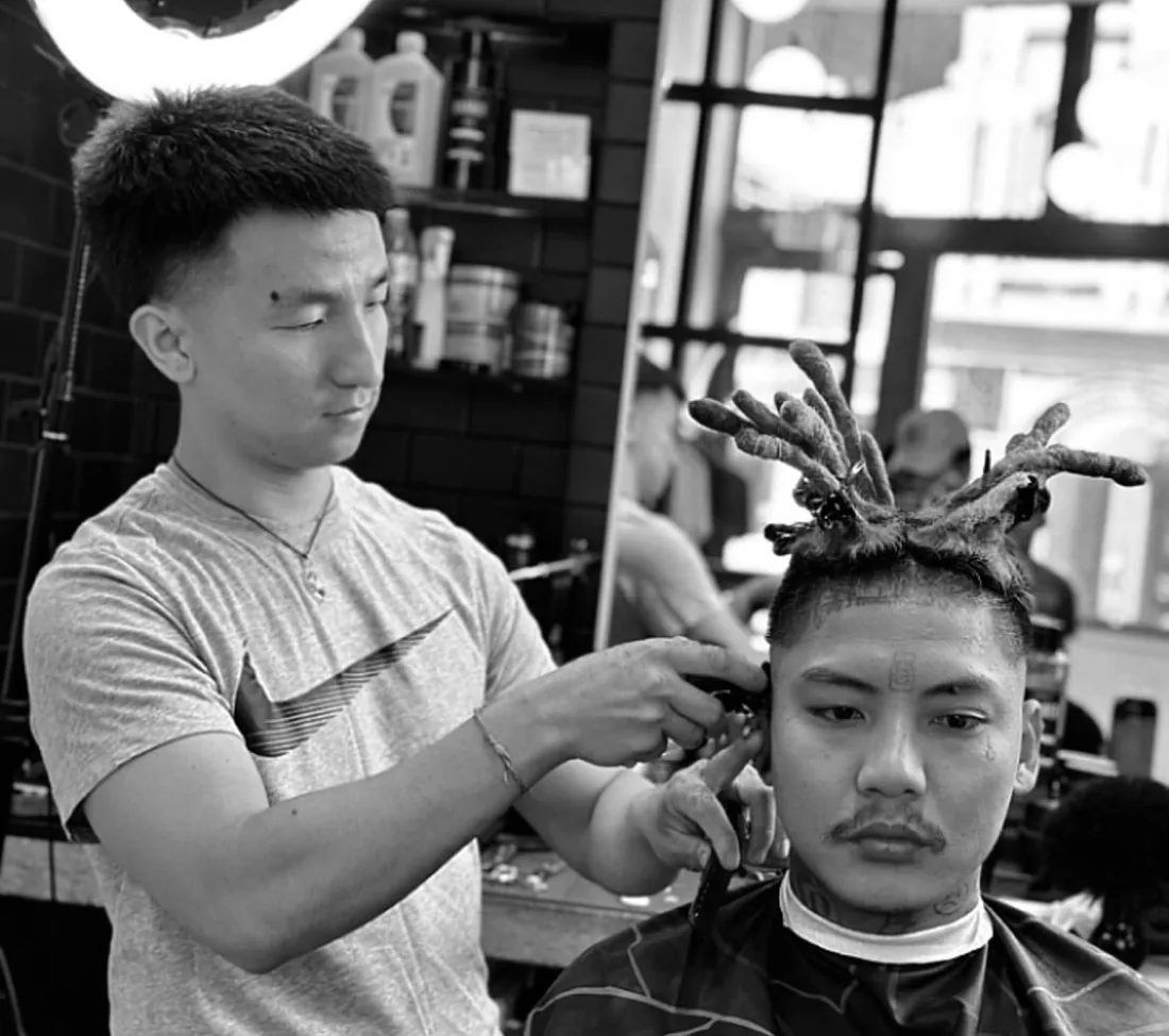 A barber styling a client's hair into twists
