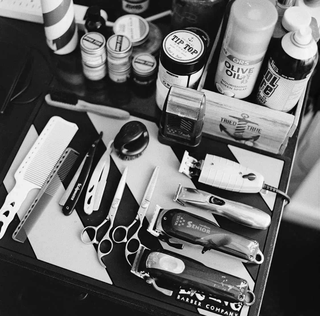 A barber's tray of combs, razors, clippers, and grooming products
